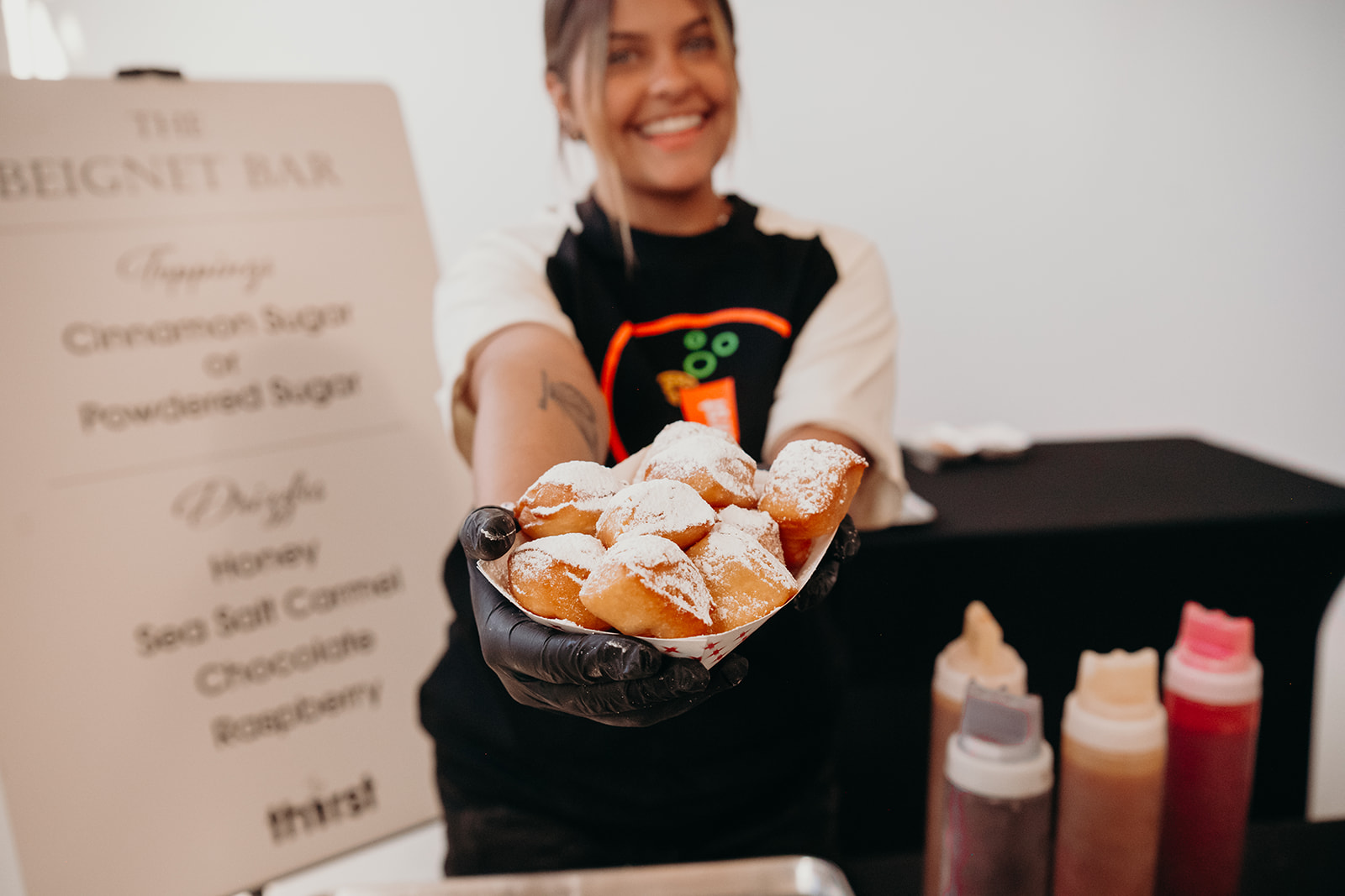 A Thirst team member holding out a tray of fresh beignets at a beignet bar