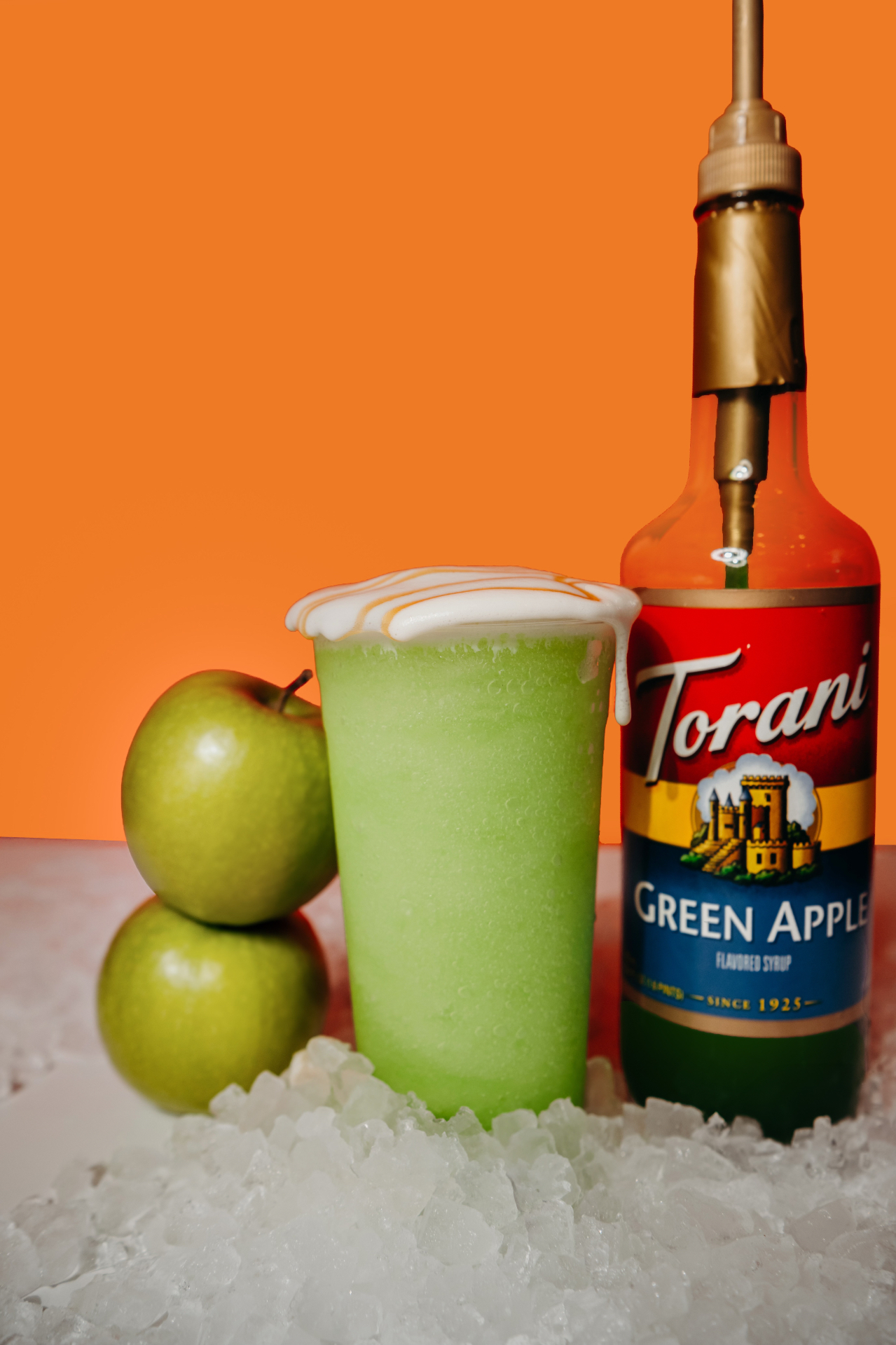 Green Apple Vibe — a blended green apple Vibe energy drink with caramel drizzle over whipped cream, next to a Torani green apple syrup bottle