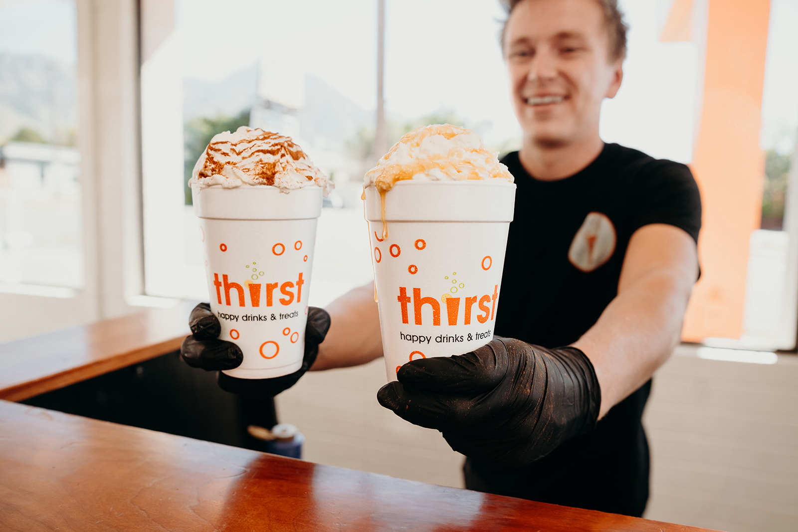 A Thirst team member holding two caramel hot chocolates