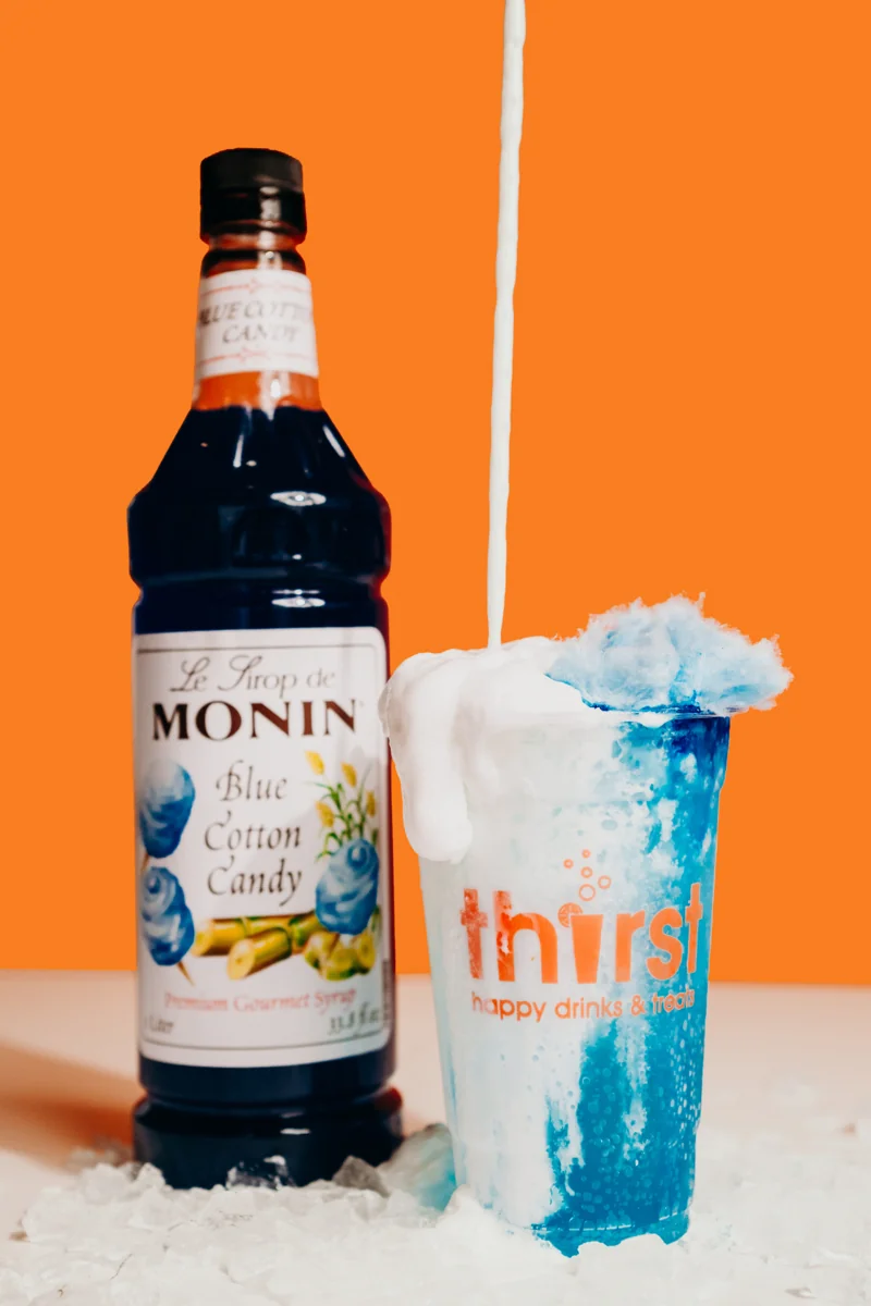Cloud Nine — a blue Sprite drink with cotton candy syrup, vanilla syrup, and vanilla cream beside a cotton candy syrup bottle