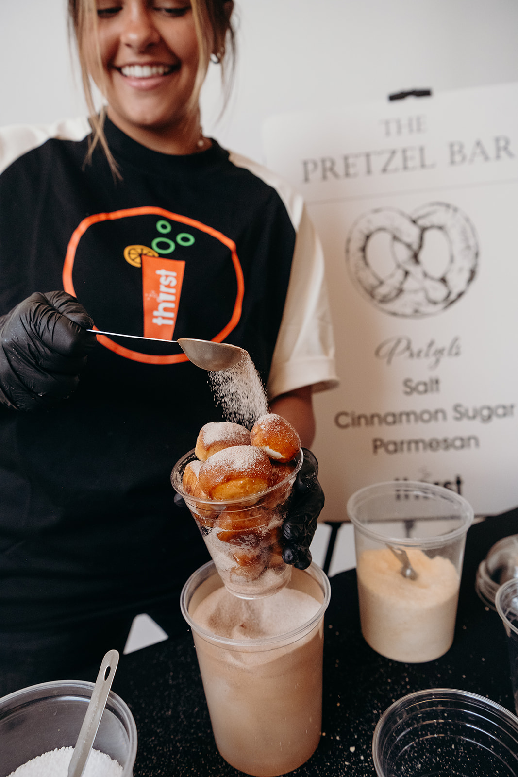 A Thirst team member dusting warm pretzel bites with cinnamon sugar at the Pretzel Bar